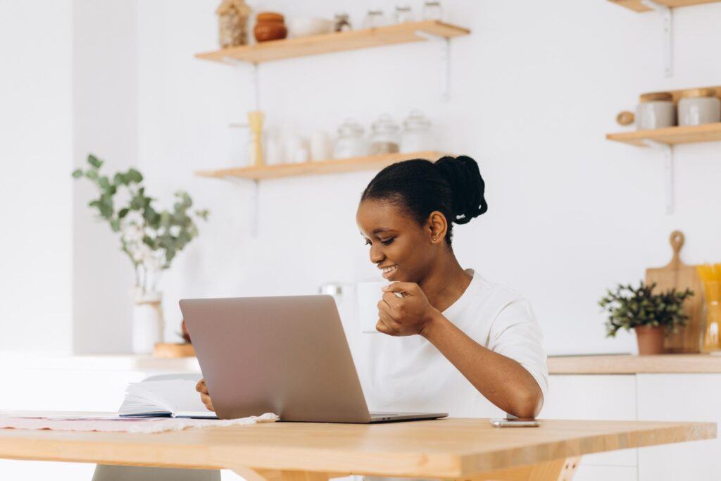 Beginner working on a laptop at a kitchen table while learning AI affiliate marketing from home